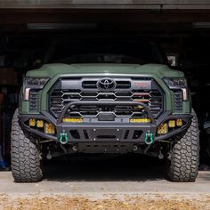 the front end of a green truck parked in a garage