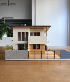 a model house sitting on top of a wooden table next to a potted plant