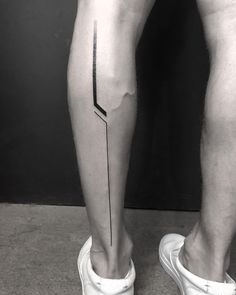 a man's legs with a black and white line tattoo on the lower leg