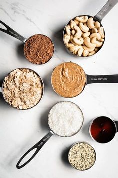 seven different types of food in bowls on a white counter top with measuring spoons