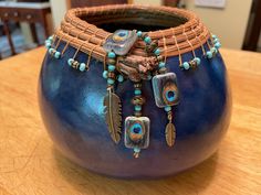 a blue vase sitting on top of a wooden table covered in beads and other items