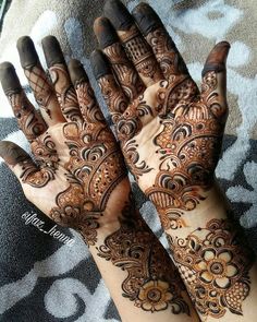 two hands with henna tattoos on them, one is showing off the intricate design