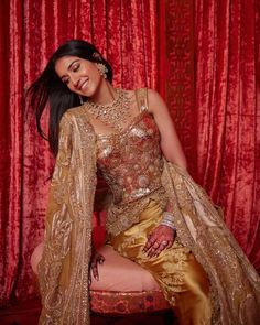 a woman sitting on top of a chair wearing a gold dress