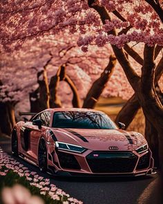 a pink sports car parked in front of cherry blossom trees with the sun shining on them