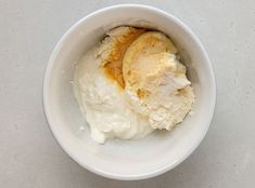 two scoops of ice cream in a white bowl on a gray table top,