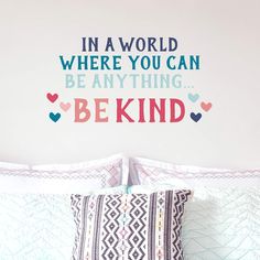 a bedroom with a wall decal that says in a world where you can be anything be kind