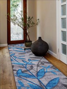 a vase sitting on top of a wooden floor next to a doorway with glass doors