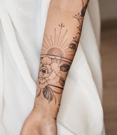 a woman's arm with a flower tattoo on it and a sunburst in the middle