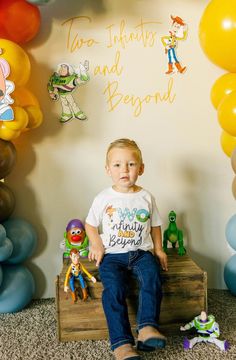 a young boy sitting on top of a wooden box in front of balloons and decorations