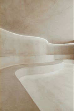 an empty room with white walls and curved concrete flooring is seen in this image