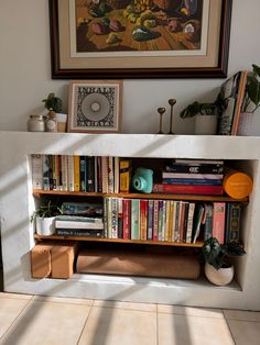 a bookshelf filled with lots of books next to a painting on the wall