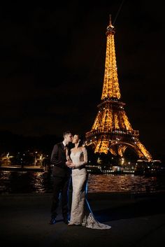 a bride and groom standing in front of the eiffel tower during their wedding night