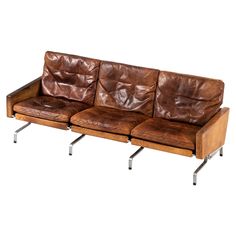 a brown leather couch sitting on top of metal legs