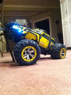 a yellow toy truck with lights on sitting in the middle of a living room floor