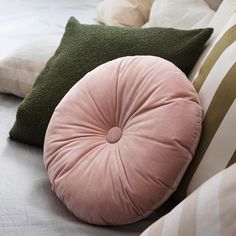 three pillows on top of a bed next to each other with green and pink accents