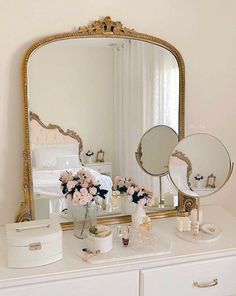 a white dresser topped with a mirror and vase filled with flowers