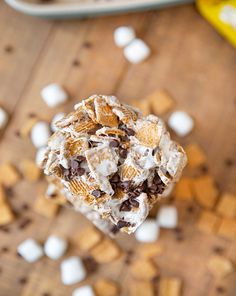 a spoon full of s'mores sitting on top of a wooden table