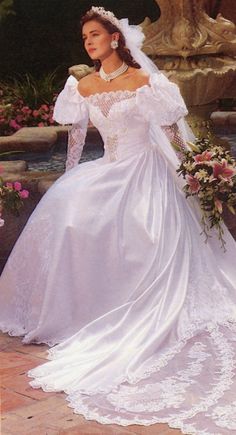 a woman in a wedding dress standing next to a fountain