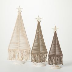 three small christmas trees with fringes and stars on top, one in white and the other in beige