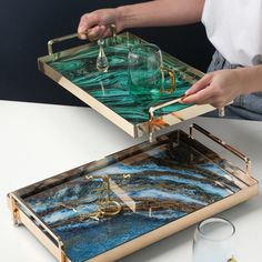 two trays that have different designs on them, one with gold handles and the other with green marble