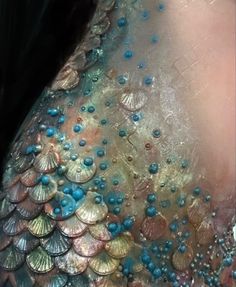 the back of a woman's dress is covered in green and silver sequins