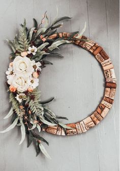 a wreath made out of wine corks with flowers and greenery on the side