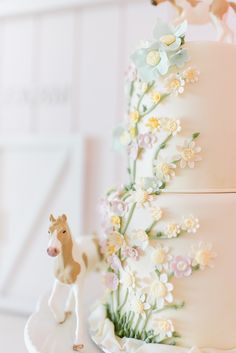 a wedding cake with flowers and a horse figurine