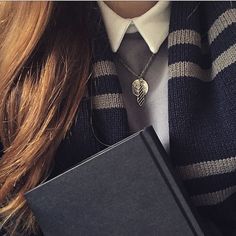 a woman wearing a tie and holding a book in her hands with a heart charm on it