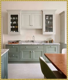 a kitchen with green cabinets and marble counter tops, along with a wooden dining table