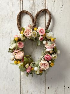 a heart shaped wreath with flowers hanging on a wall