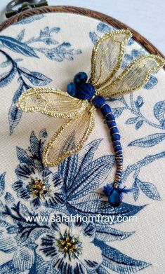 a blue and gold dragonfly on white fabric