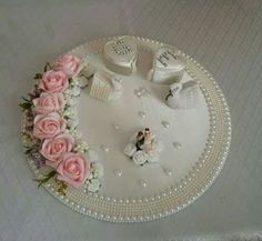 a wedding cake with pink roses and white shoes on it's side, sitting on a table