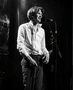 a man standing in front of a microphone with his hands on his hips and smiling