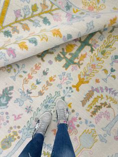 a person standing on top of a rug next to a white and yellow wallpaper