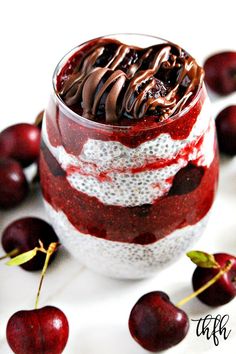 a dessert in a glass with chocolate and cherries around it