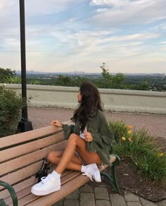 a woman sitting on top of a wooden bench