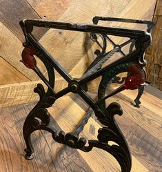 an ornate iron shelf with red glass knobs on the top and bottom, against a wooden wall