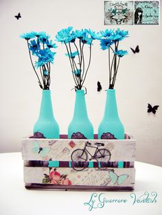 three blue vases with flowers in them are sitting on a table next to butterflies