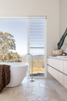 a large white bath tub sitting in a bathroom next to a window with an open sliding glass door