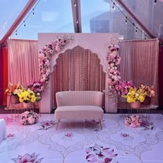 a pink couch sitting in front of a white wall with flowers on it and an arch