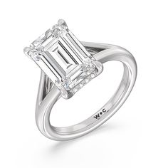 an emerald - cut diamond ring with diamonds on the band and shoulders, set in 18k white gold