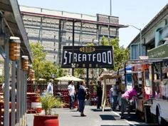 food trucks are lined up on the side of the road near buildings and people walking down the street