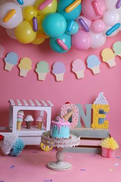 there is a birthday cake and balloons on the table in front of the ice cream stand