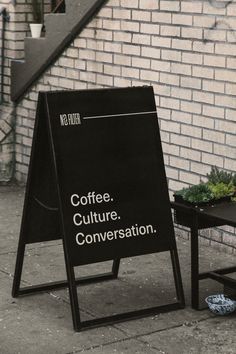 a sign sitting on the side of a building next to a small table and chair