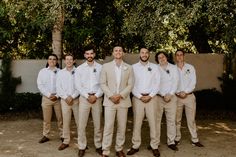 a group of men standing next to each other wearing white shirts and khaki pants