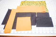 several pieces of fabric sitting on top of a cutting board next to a knife and ruler