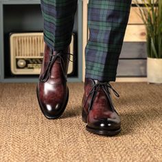 a man in plaid pants and brown shoes is standing on the carpet with his feet up