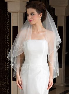 a woman in a white wedding gown and veil posing for the camera with her hand on her hip