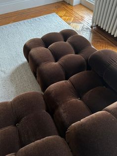 a brown couch sitting on top of a wooden floor next to a radiator