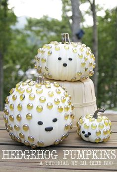 three white pumpkins with gold rivets stacked on top of each other in front of trees